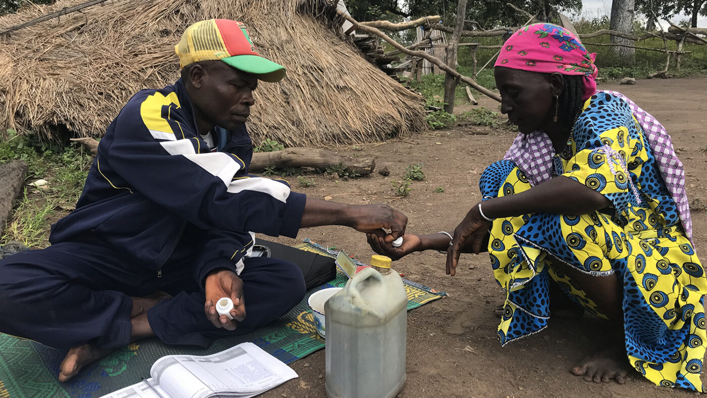 A man gives a woman treatment to protect her from neglected tropical diseases.