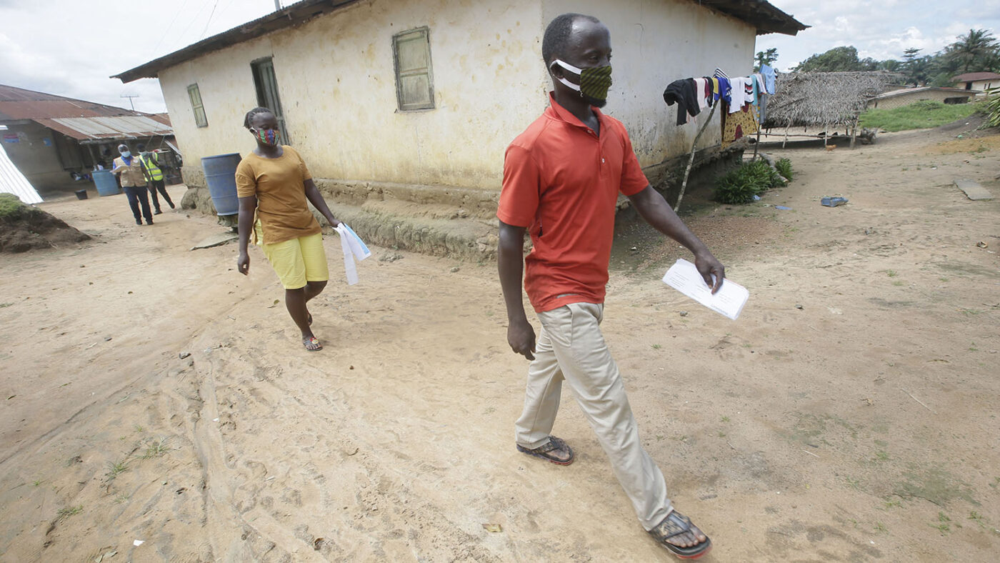 Two community volunteers, male and female, walk through the community.
