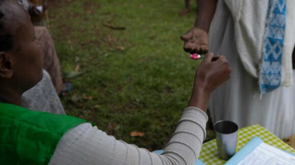 Woman gives man tablets on a teaspoon