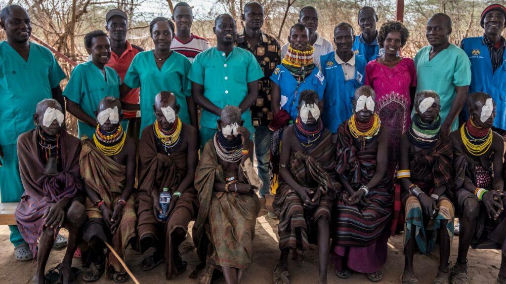 Surgeons and surgery patients wearing bandages over their eyes line up for a photograph