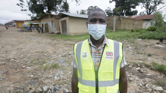 A man stands for a portrait while wearing a mask.
