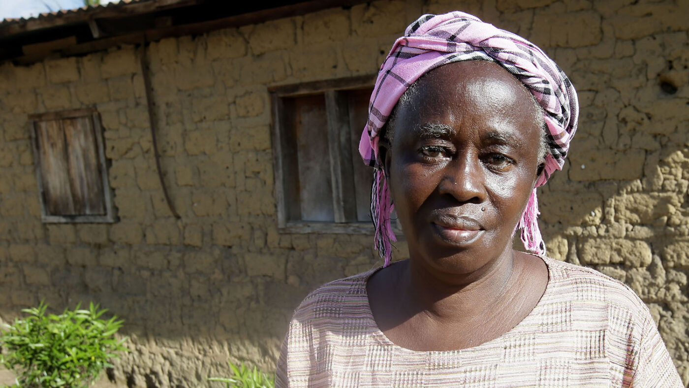 An elderly woman stands for a portrait.