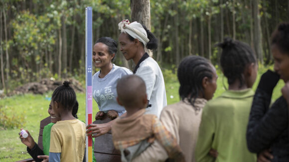 a group of people wait to be measured with a dose pole.