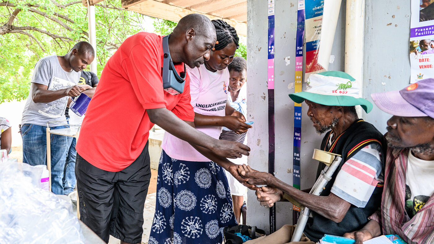 A community volunteer gives a man some medication.