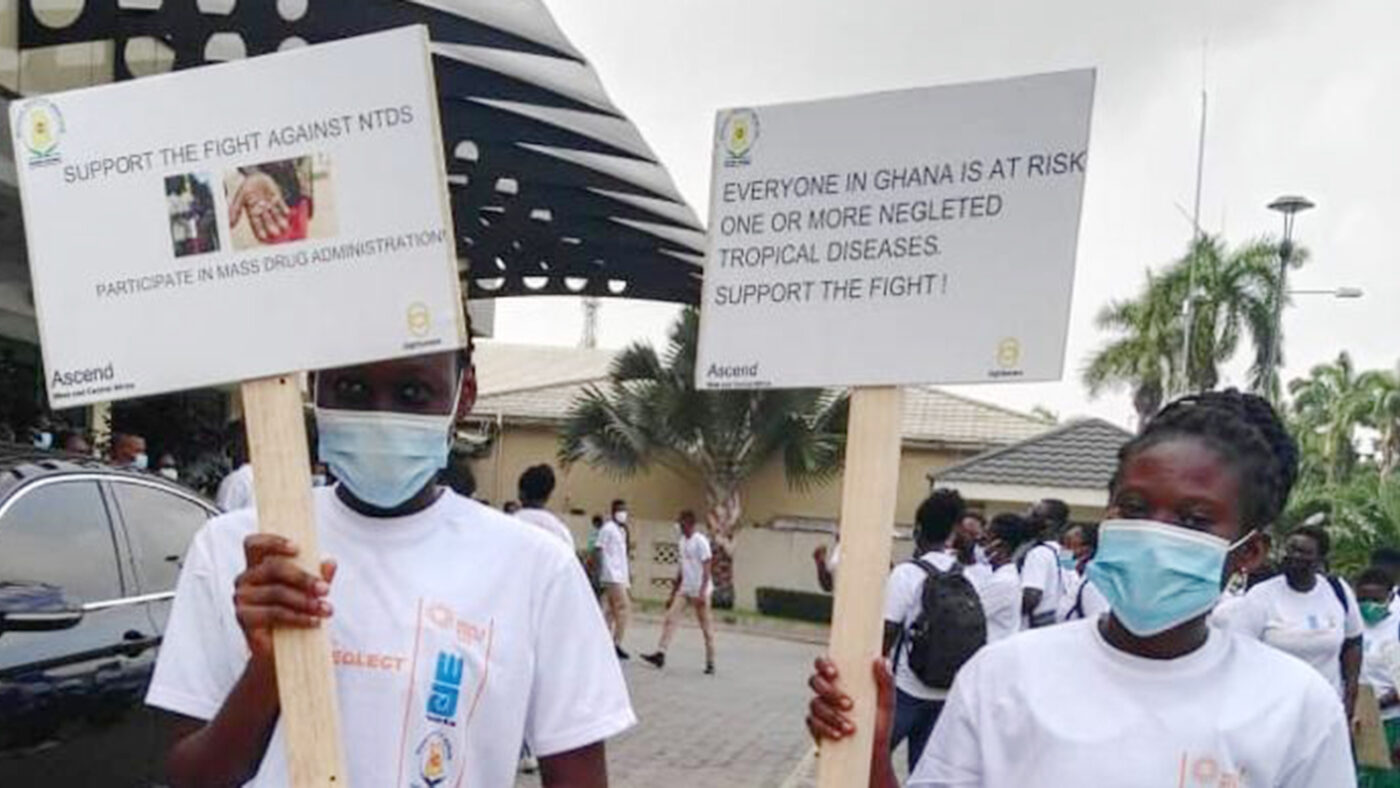 Two young women holding signs to raise awareness of neglected tropical diseases in Ghana.