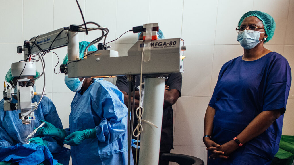 A surgeon watches on as trainee doctors operate on a patient.