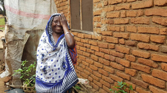 Amina covers one eye with her hand and smiles after cataract surgery.