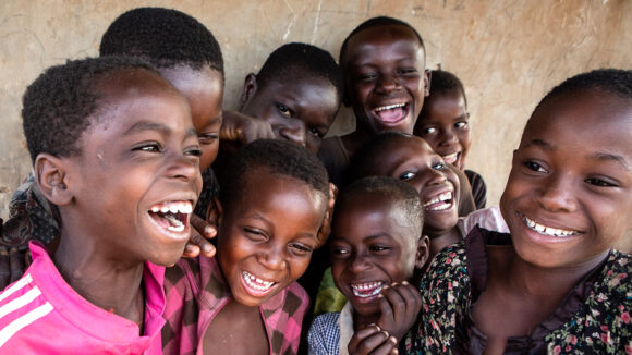 A group of children in Ghana laugh and smile.