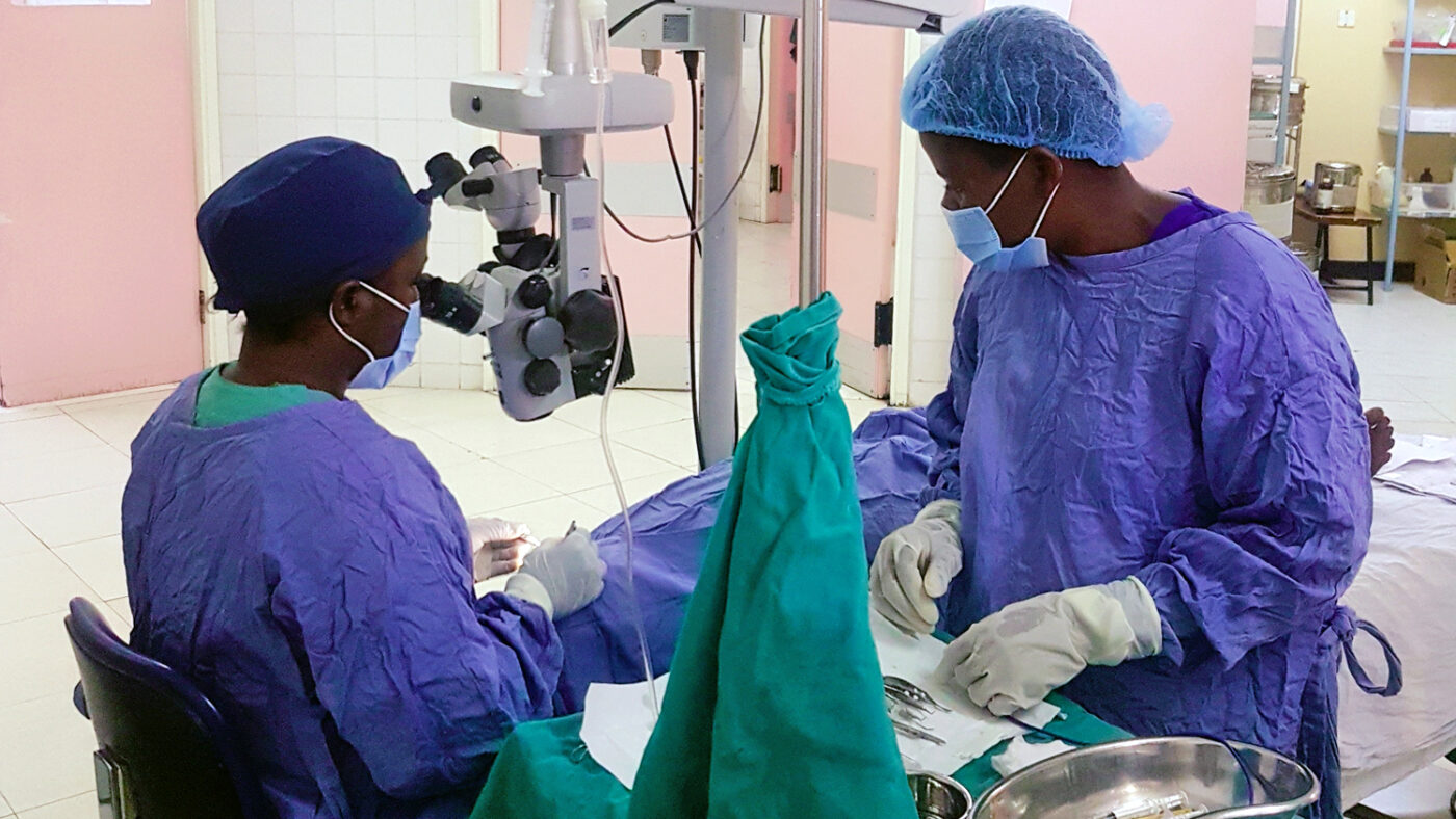 Two surgeons in scrubs and masks carrying out cataract surgery in Malawi.