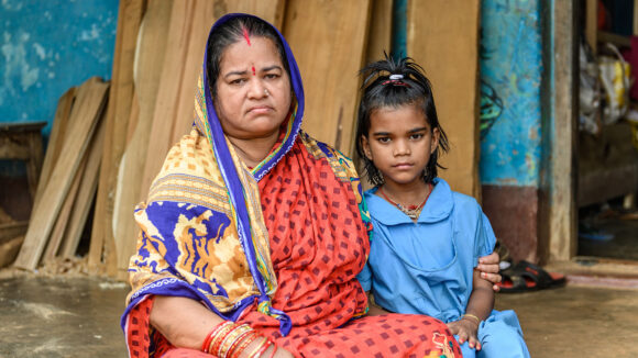 Archana sits with her grandmother. Grandmother has her arm around Archana.