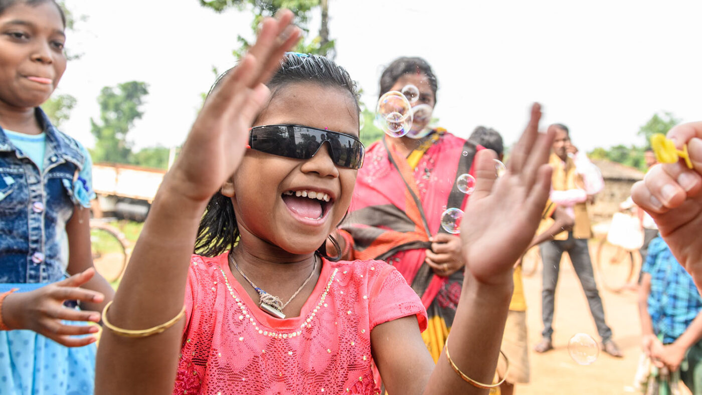 Archana is wearing protective glasses and happily chasing bubbles.