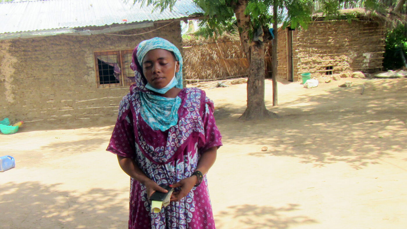 Viki Wilonge Hussene stands outside her home.