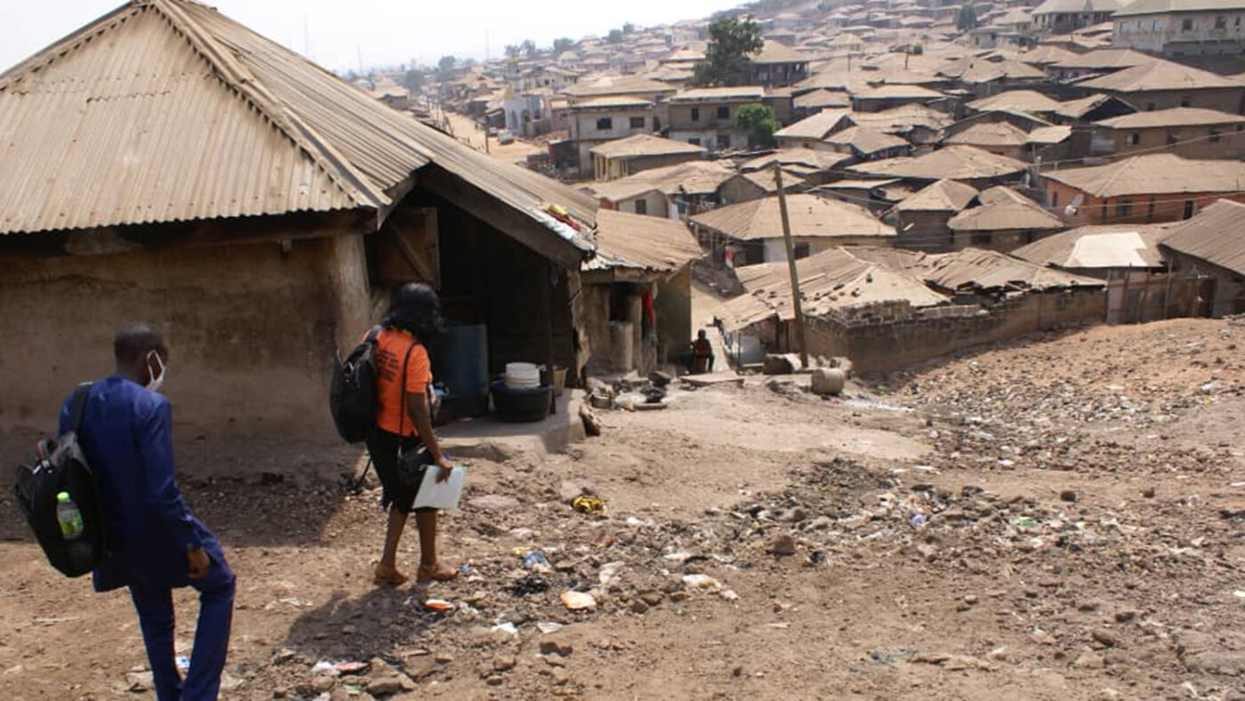 A steep dusty road flanked by huts on each side.