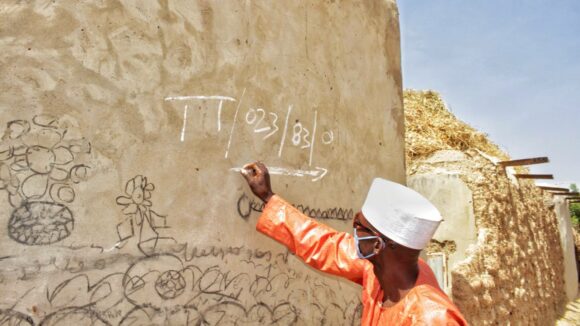 A man marks outside of a house to confirm trachoma surgery.
