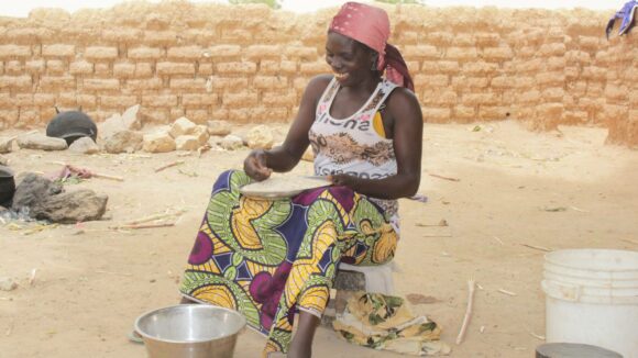 A woman laughing while she prepare food outside