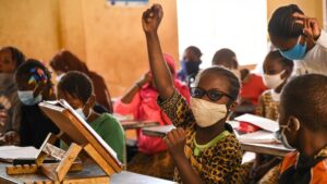 A young girl raising her hand in a classroom.