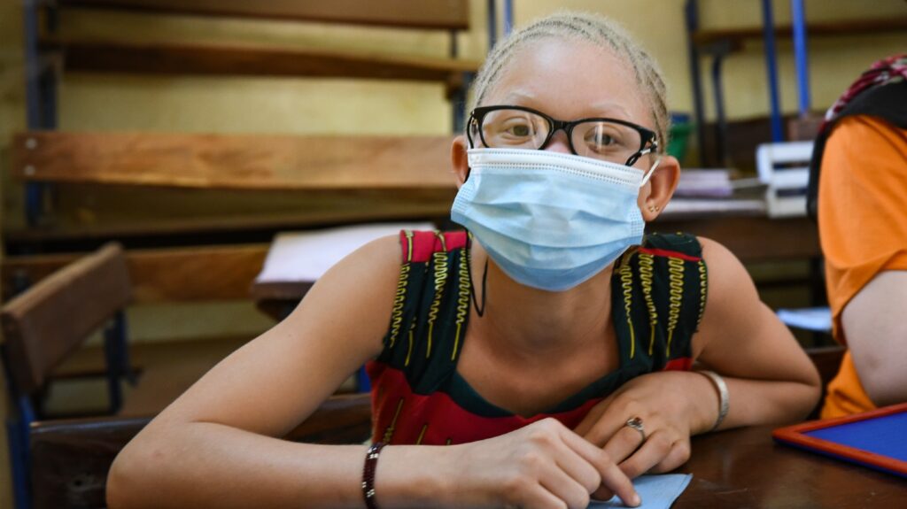 Close up portrait of a young girl wearing a mask and glasses.