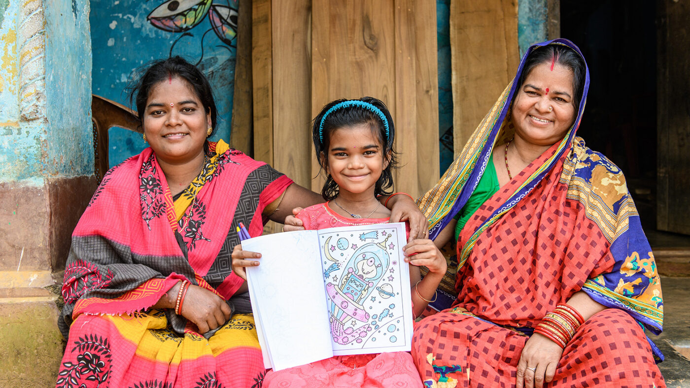 Archana with her family looking happy sat outside their home.