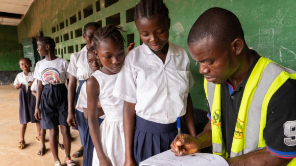 School children in a queue have their information taken by a man