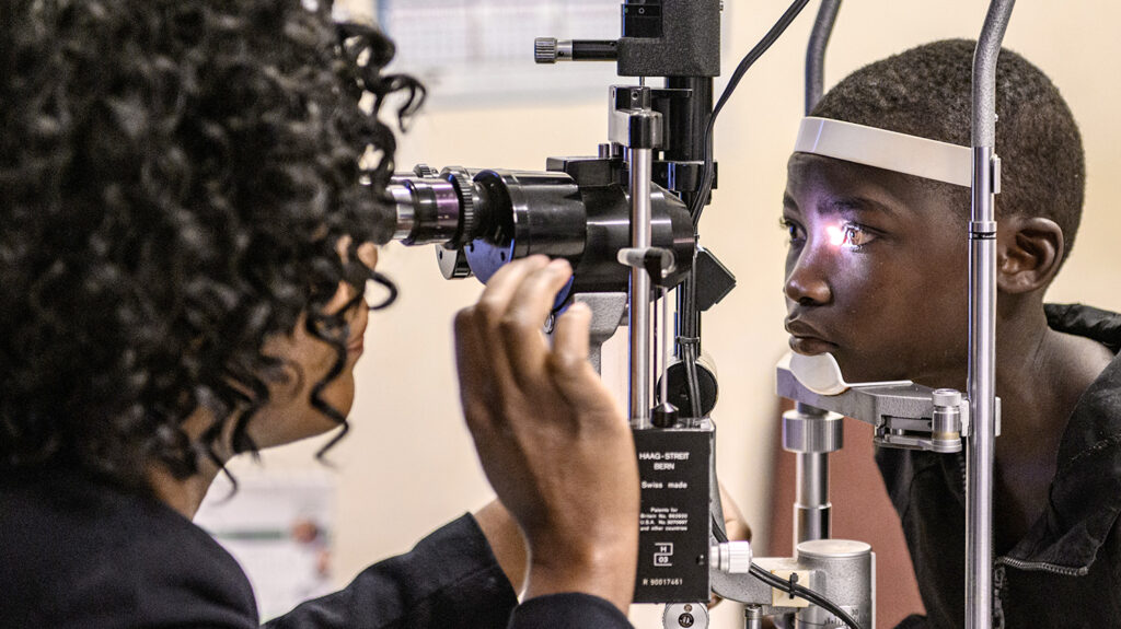 Mary has her eyes checked by an eye health worker.