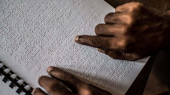 A hand tracing over the raised bumps of braille.