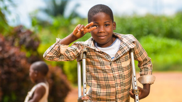 A young boy smiles and waves at the camera.