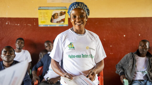 Philomene, a volunteer community-directed distributor, stands smiling inside Massangam hospital