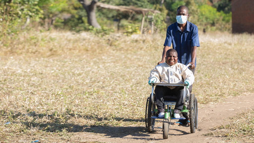 Chikumbutso Diverson escorting his son, Enock, to school in an adapted wheelchair.