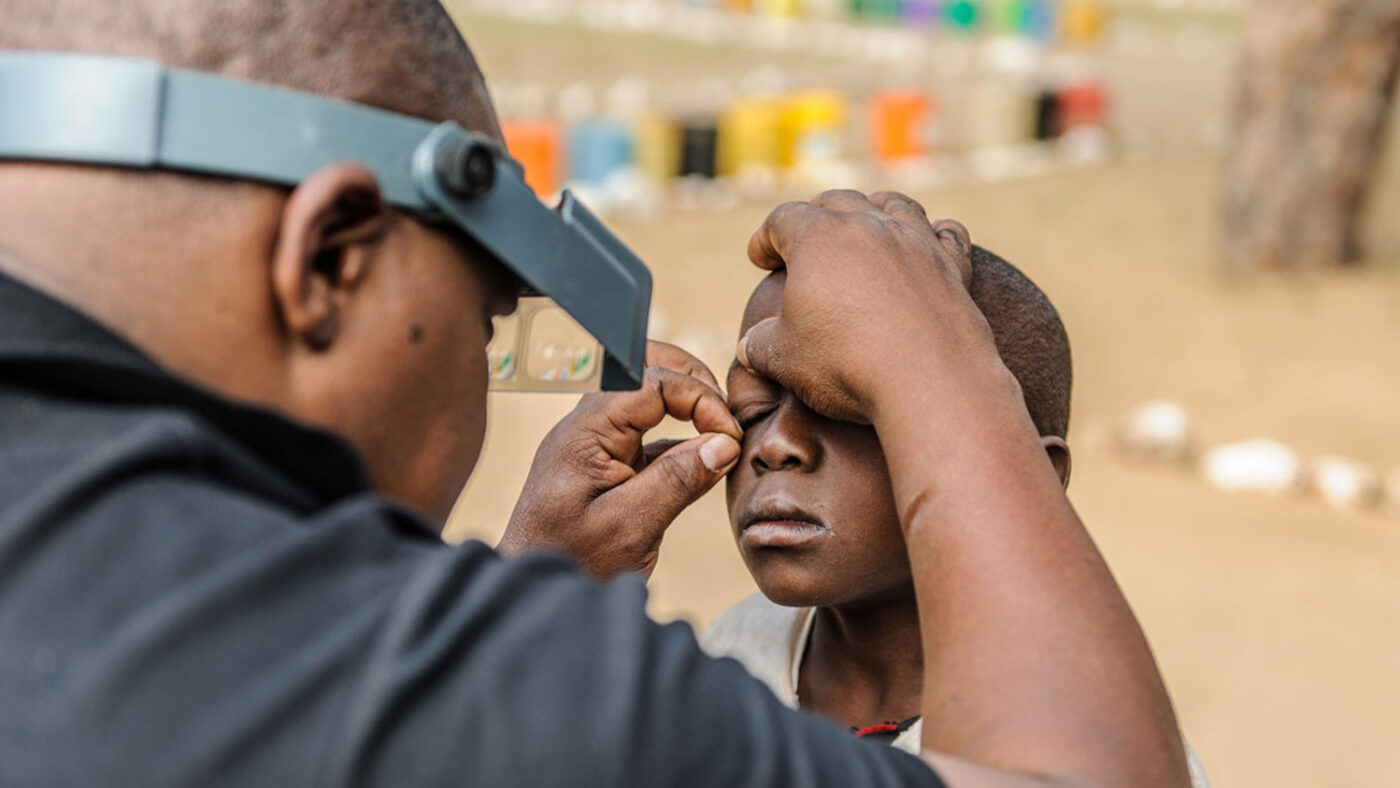 A young child has their eye held open during an eye examination.