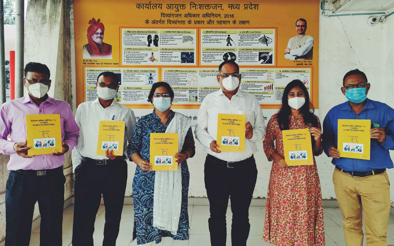 A group of six people stand together each holding a sign.
