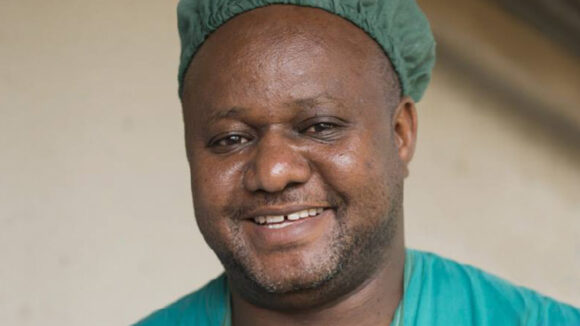 Dr Sencodri Njau smiles while wearing surgical scrubs.