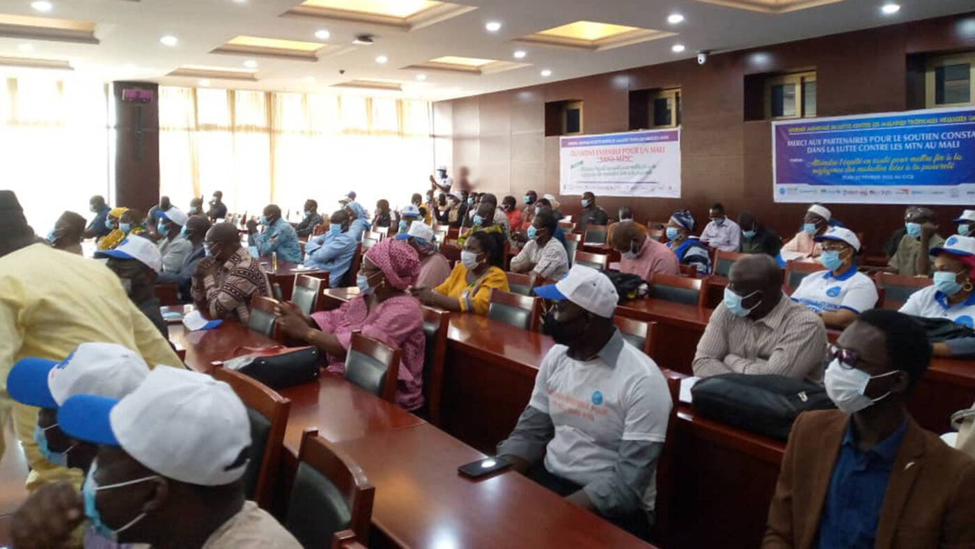 A large group of people sit in a lecture theatre wearing medical masks.