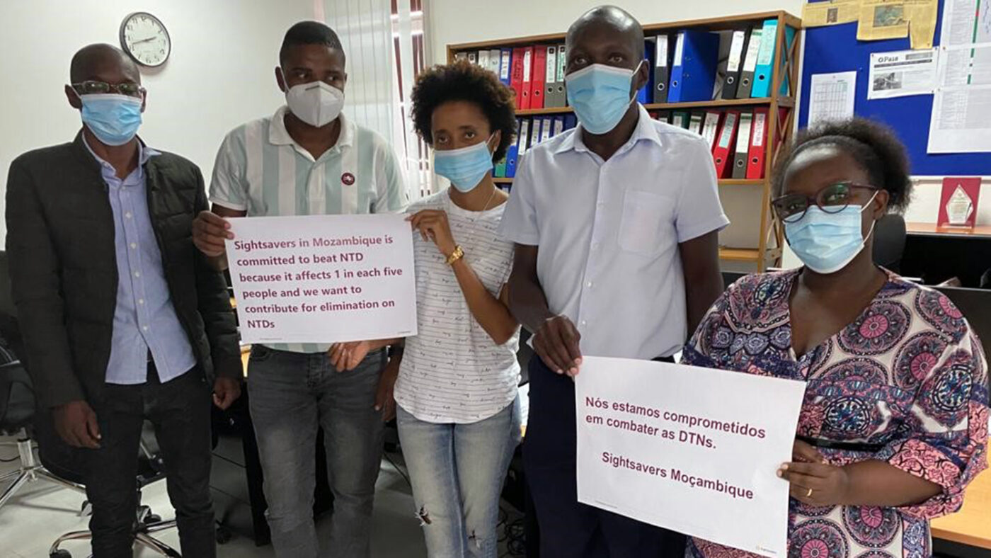 Five members of Sightsavers staff pose for a photograph with placards showing their commitment to beating NTDs.