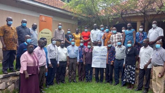 A large group of staff and health workers gather for a group photograph outside.