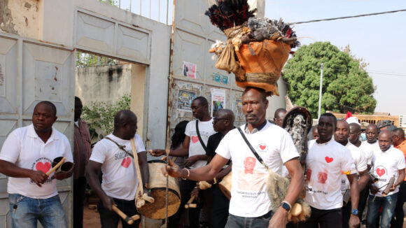 A group of performers with traditional instruments and clothing parade outside.