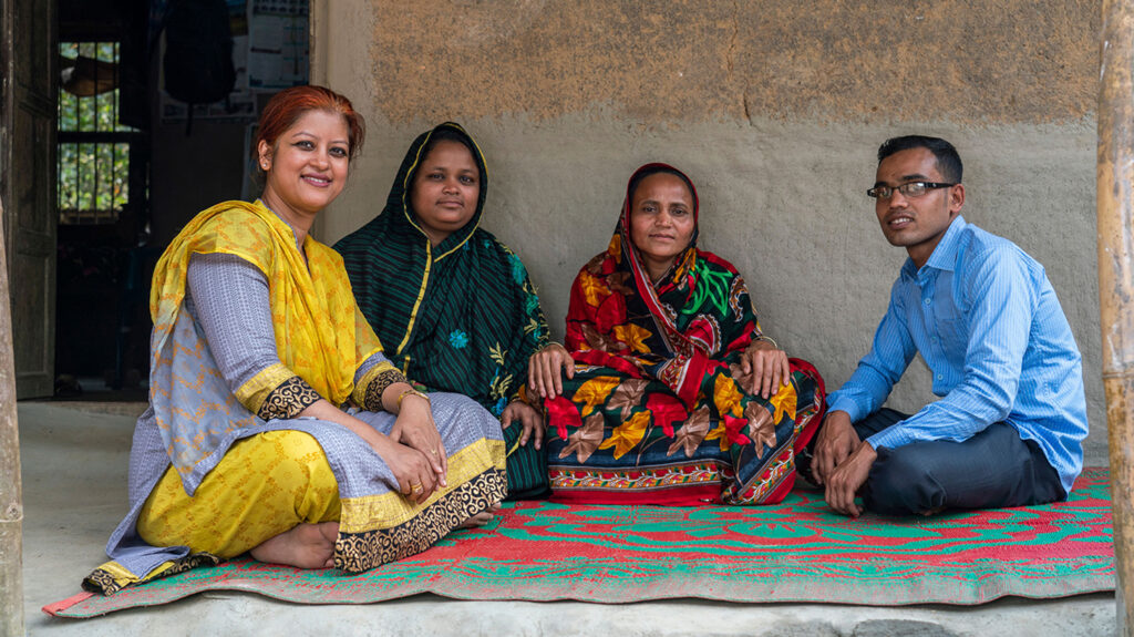 Asma sits with Arif and two female members of his family outside their home.