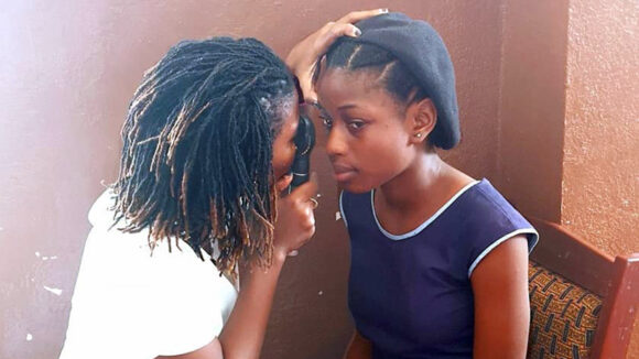 Dr Jalikatu uses a magnifier to look at a girl's eyes.