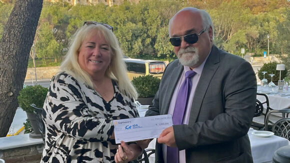 Dr Caroline Harper hands a cheque to Yannis Vardakastanis, president of IDA.