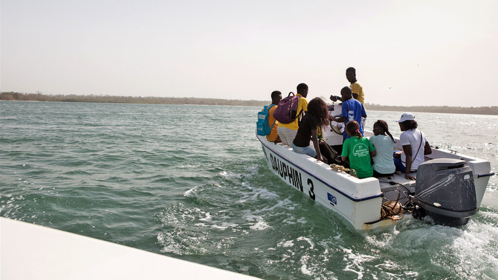 A group of community volunteers aboard a small motor boat in the middle of the sea, on their way to the Bijagos islands in Guinea-Bissau.
