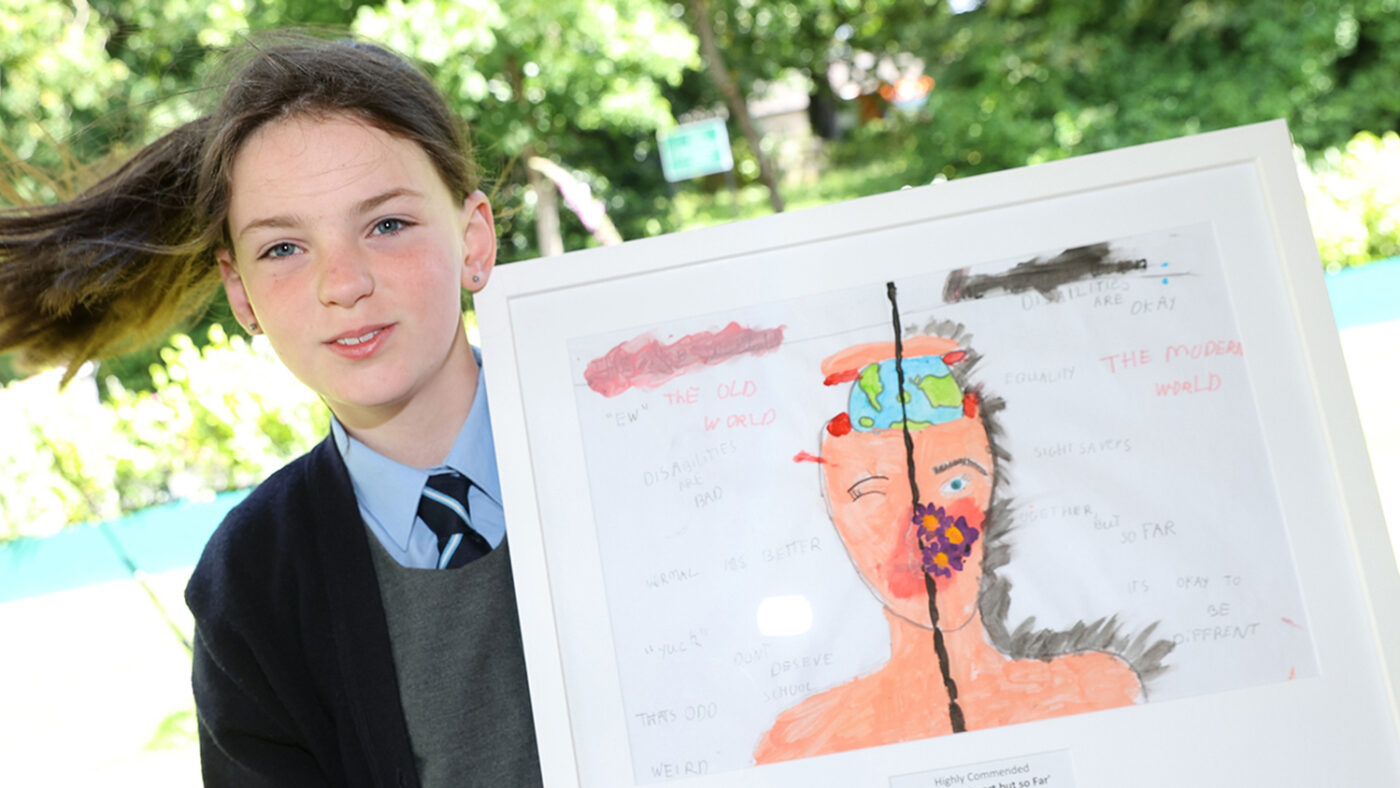 Sarah holds her framed painting, which depicts the different ways a person with disabilities can be represented.