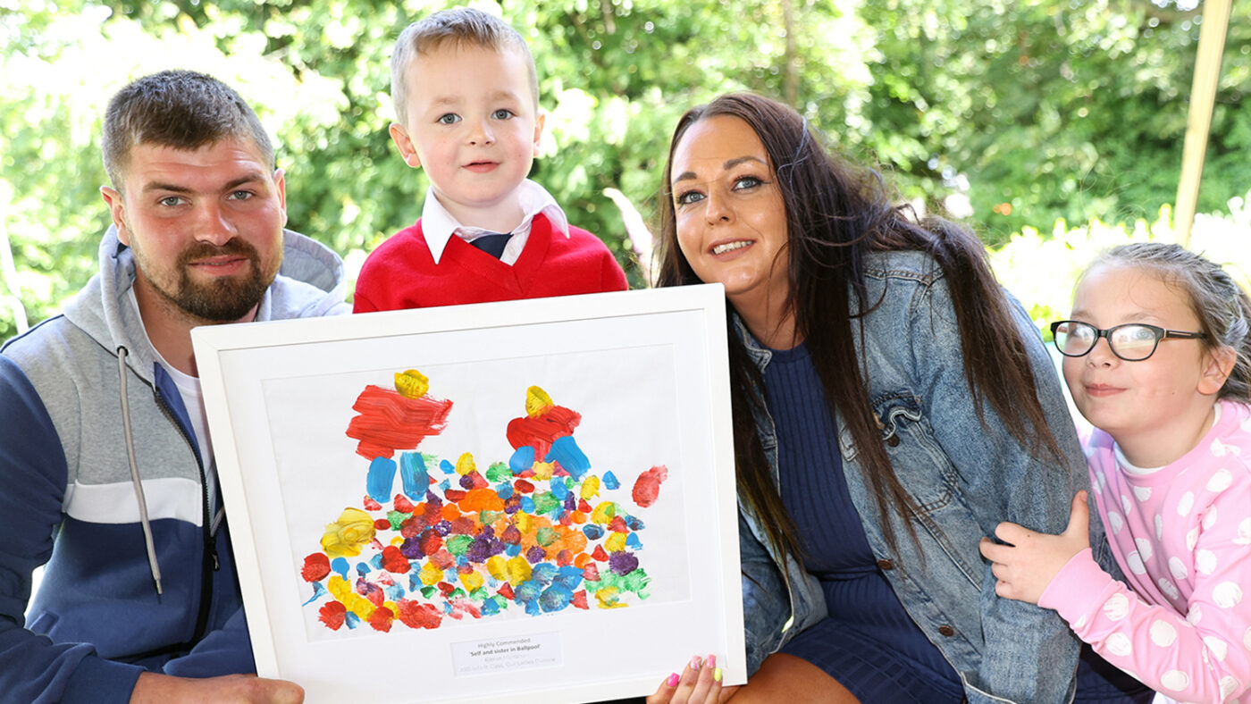 Kieran and three members of his family smile as they hold his framed abstract painting.