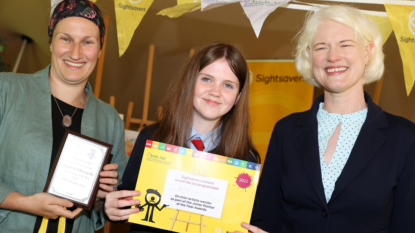 Aoife smiles as she stands between the two female judges, as she receives her award certificate.