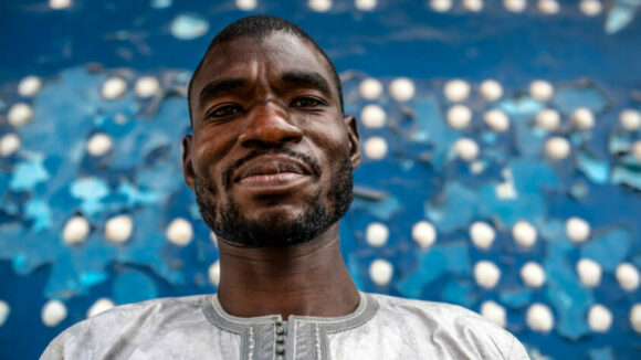 Soulé, an elementary school teacher from Senegal stands in front of a braille board.
