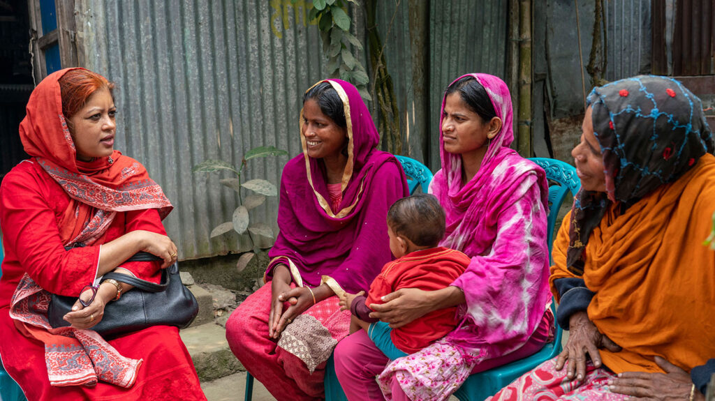 Asma sits outside with Shamima and her family.