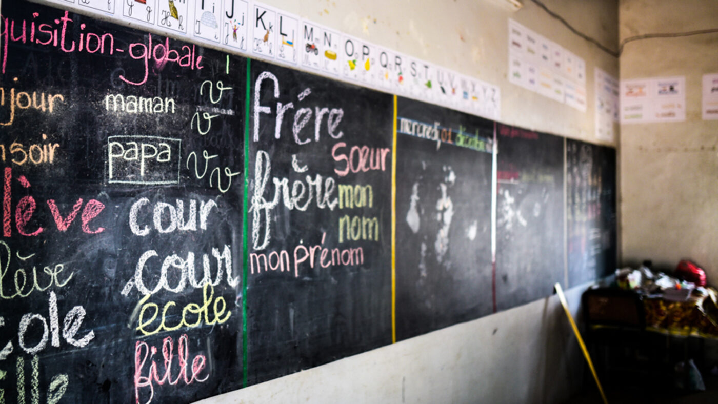 A blackboard in a classroom with large writing all over it.