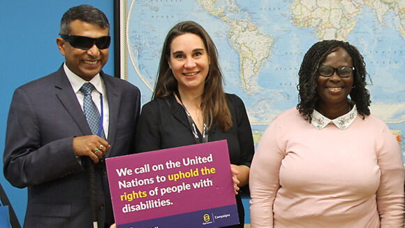 Sightsavers staff at the UN hold signs saying 'We call on the United Nations to uphold the rights of people with disabilities'.