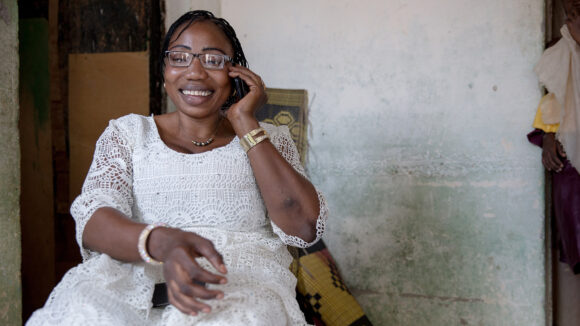 A woman sits talking on a mobile phone.