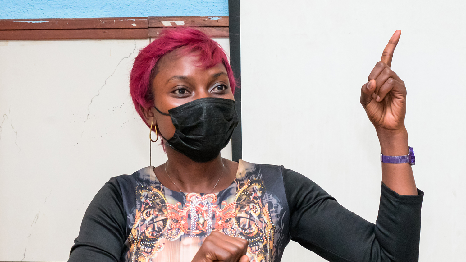 Leonie speaking in a workshop. She's wearing a mask and holding her finger in the air.