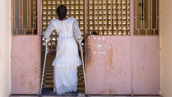 A woman with crutches walks into a building.