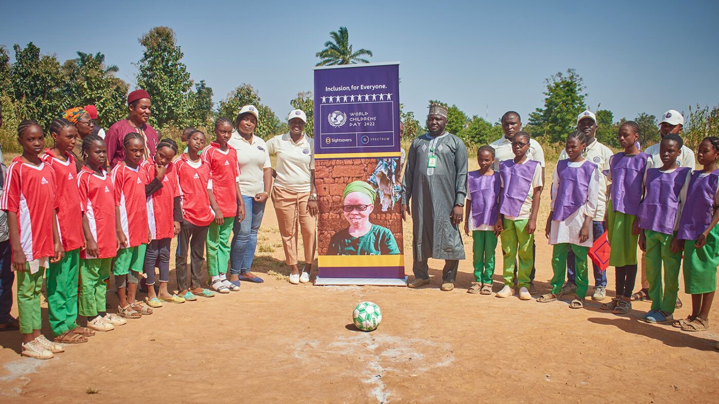 Schoolchildren and teachers pose for a group photo alongside a banner for World Children's Day.